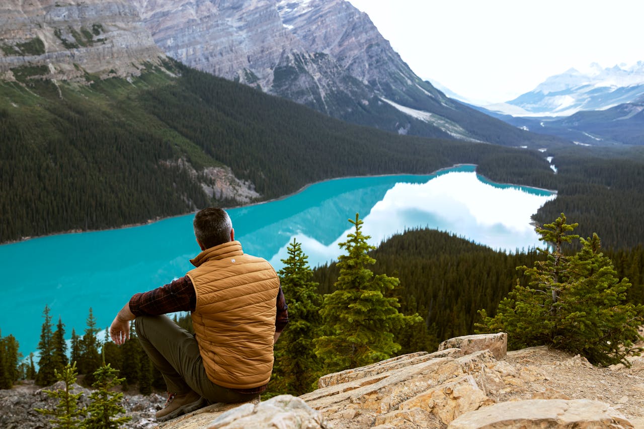 A man sits overlooking the breathtaking view of Peyto Lake in Banff National Park, Canada.
